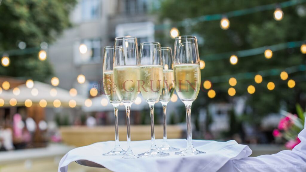 Kieliszki z prosecco na tacy kelnera, w tle girlandy świetlne