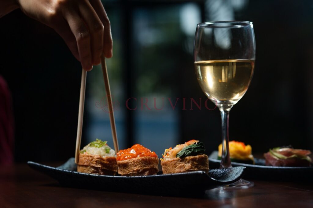 Zestaw sushi i kieliszek białego wina na ciemnym stole w restauracji